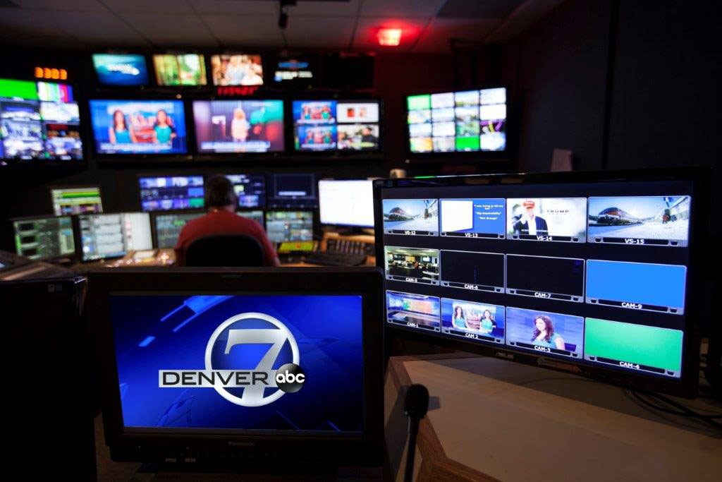 Photo of the control room for ABC Denver 7 lit up on the screens with a man sitting at a desk monitoring the screens